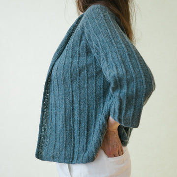 A woman wearing a handknitted cardigan, details seen from the side