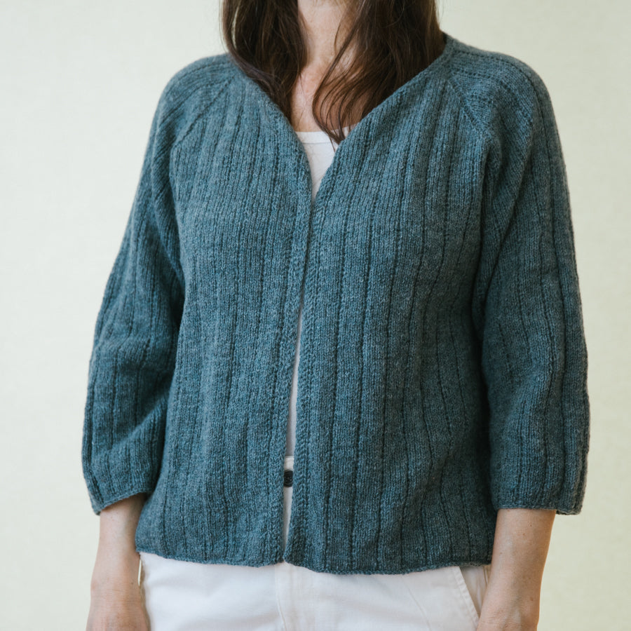 A woman wearing a handknitted cardigan, details seen from the front
