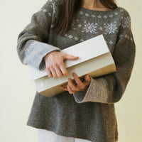 A woman wearing a handknitted sweater showing a gift box