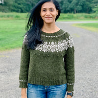 A young woman is wearing a handknitted sweater in dark green, seen from the front