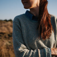 A woman wearing a handknitted Biches & Bûches sweater, seen from the front