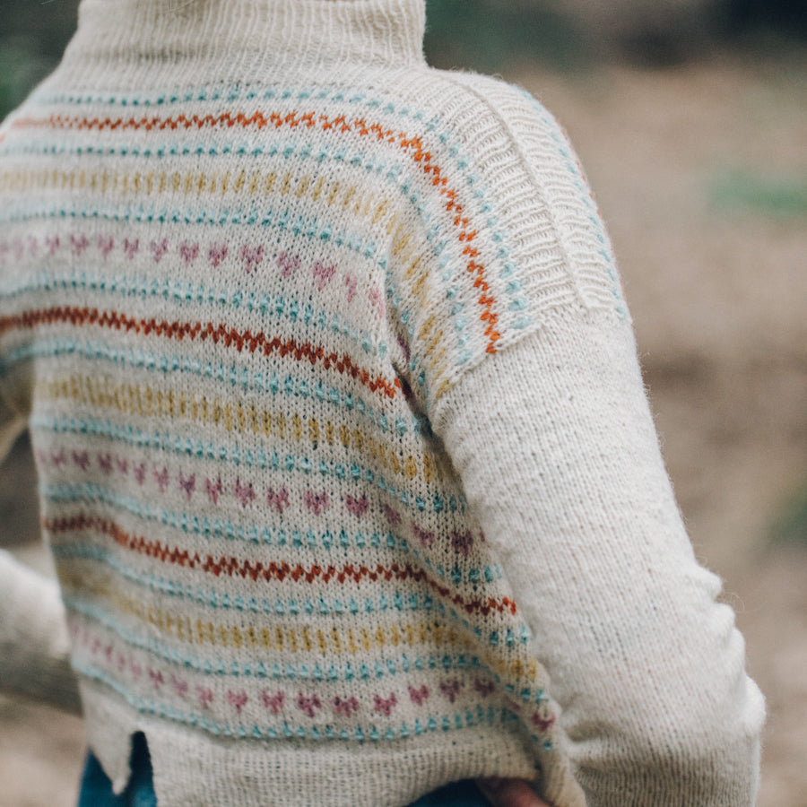 Andrea Mowry is wearing a stranded handknitted sweater, seen from the back